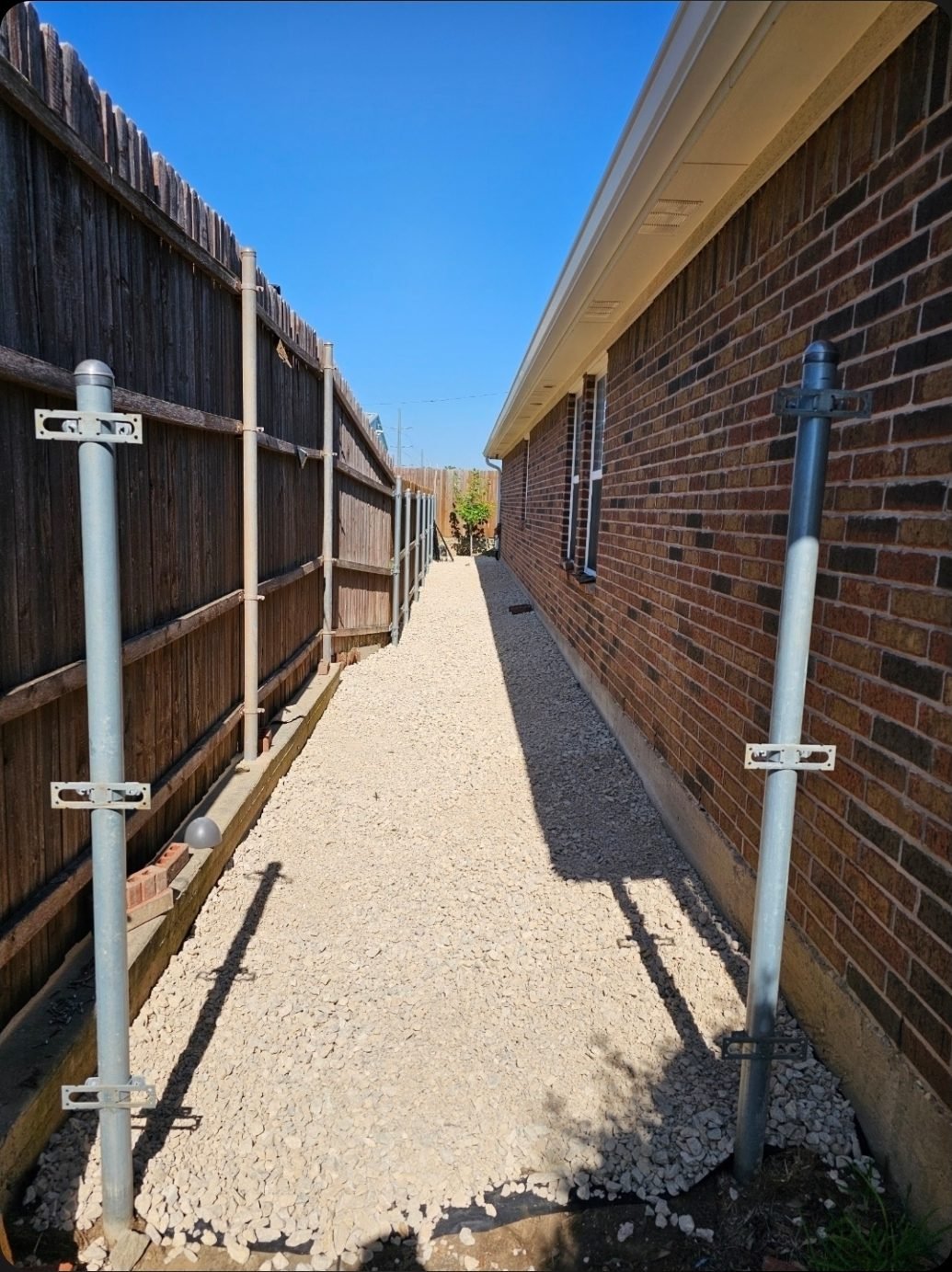 Compacted aggregate base covering a completed French drain in a narrow side yard